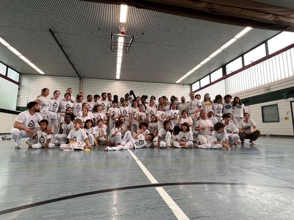 Group photo of Simplesmente Capoeira Berlin – kids and adults in the gym